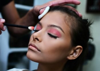woman with pink lipstick holding white and purple toothbrush