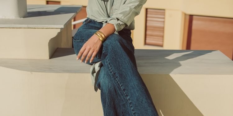 a woman sitting on a ledge with her legs crossed
