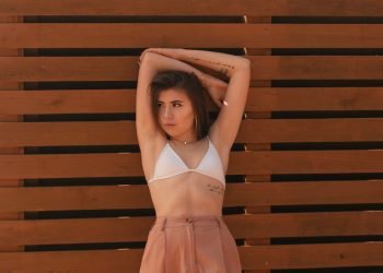 woman in orange dress standing beside brown wooden wall