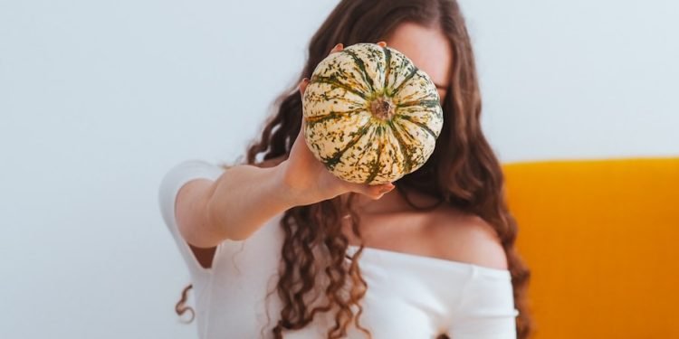woman in white crop top and blue denim daisy dukes with brown and yellow sunflower headdress