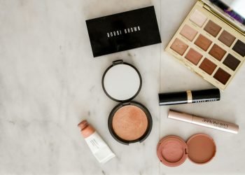 photo of assorted makeup products on gray surface