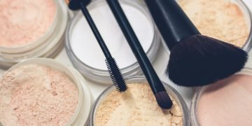 three makeup brushes on top of compact powders