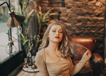 woman in brown long sleeve shirt and gray skirt sitting on brown leather couch