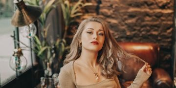 woman in brown long sleeve shirt and gray skirt sitting on brown leather couch