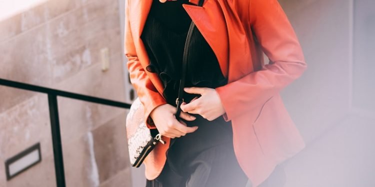 woman wearing orange jacket and black pants with black inner shirts