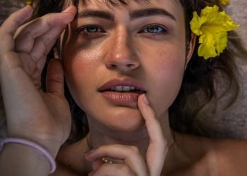 woman in gray tank top holding yellow flower