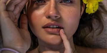 woman in gray tank top holding yellow flower