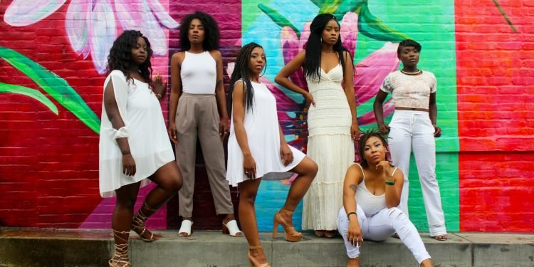 six women wearing white pants posing