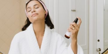 woman in white bathrobe holding smartphone
