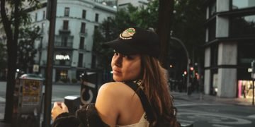a woman standing on a sidewalk looking at her cell phone