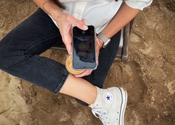 a woman sitting on the ground holding a cell phone