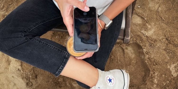 a woman sitting on the ground holding a cell phone