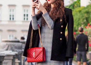 woman in black coat holding red leather handbag