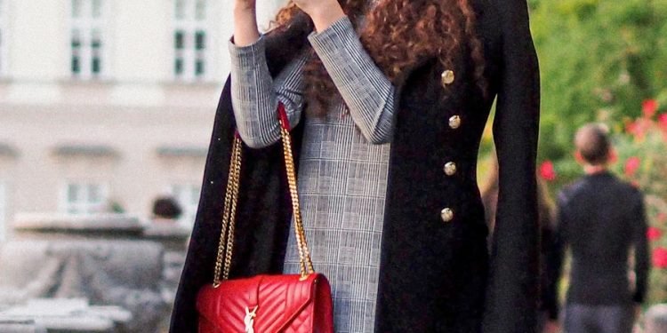 woman in black coat holding red leather handbag