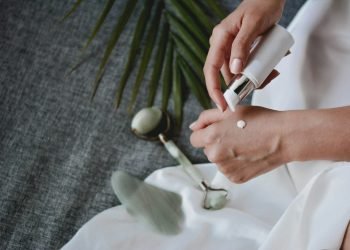 person holding white plastic bottle pouring white liquid on white ceramic mug