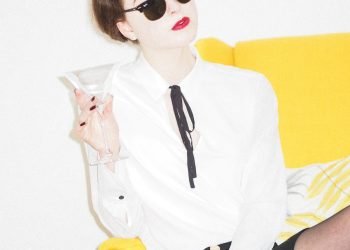 woman in white dress shirt and black skirt sitting on yellow couch