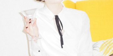 woman in white dress shirt and black skirt sitting on yellow couch