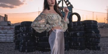 a woman standing in a field next to a pile of tires